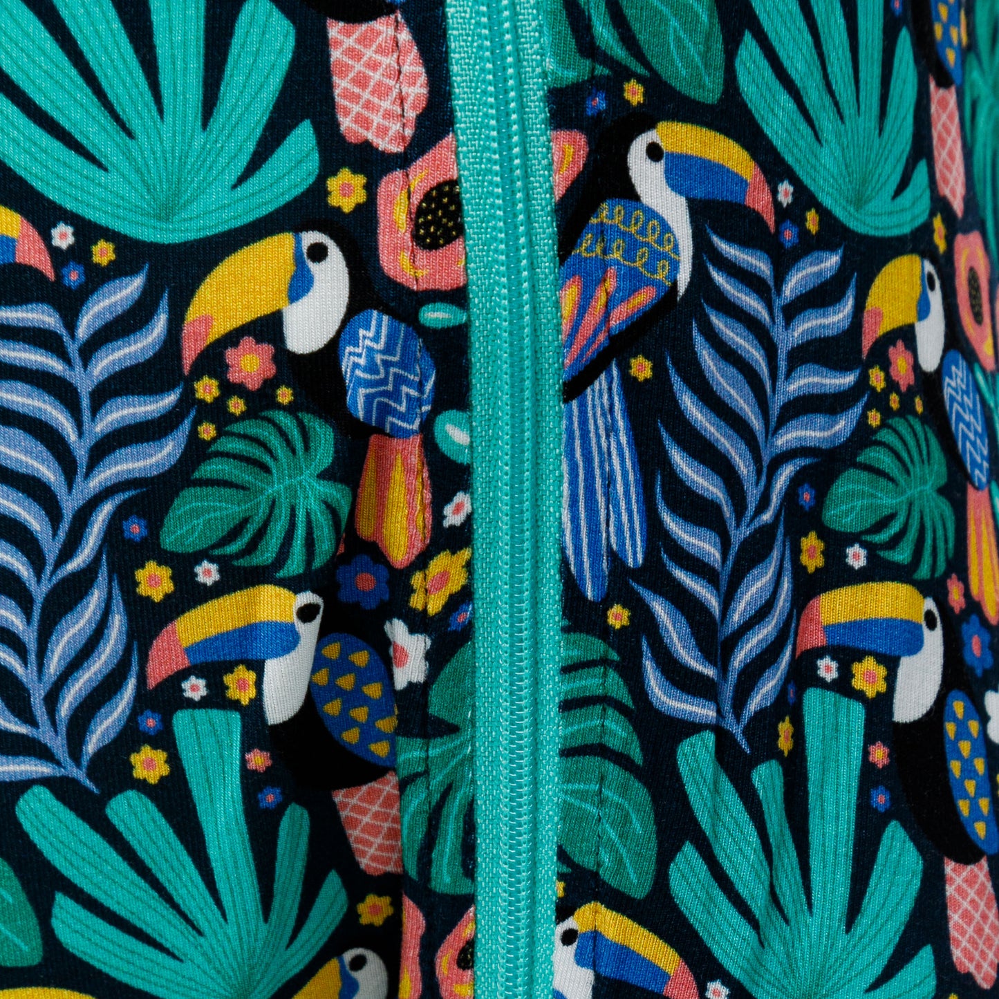 Vedere de aproape a fermoarului pe body-ul pentru bebeluși cu model tropical.