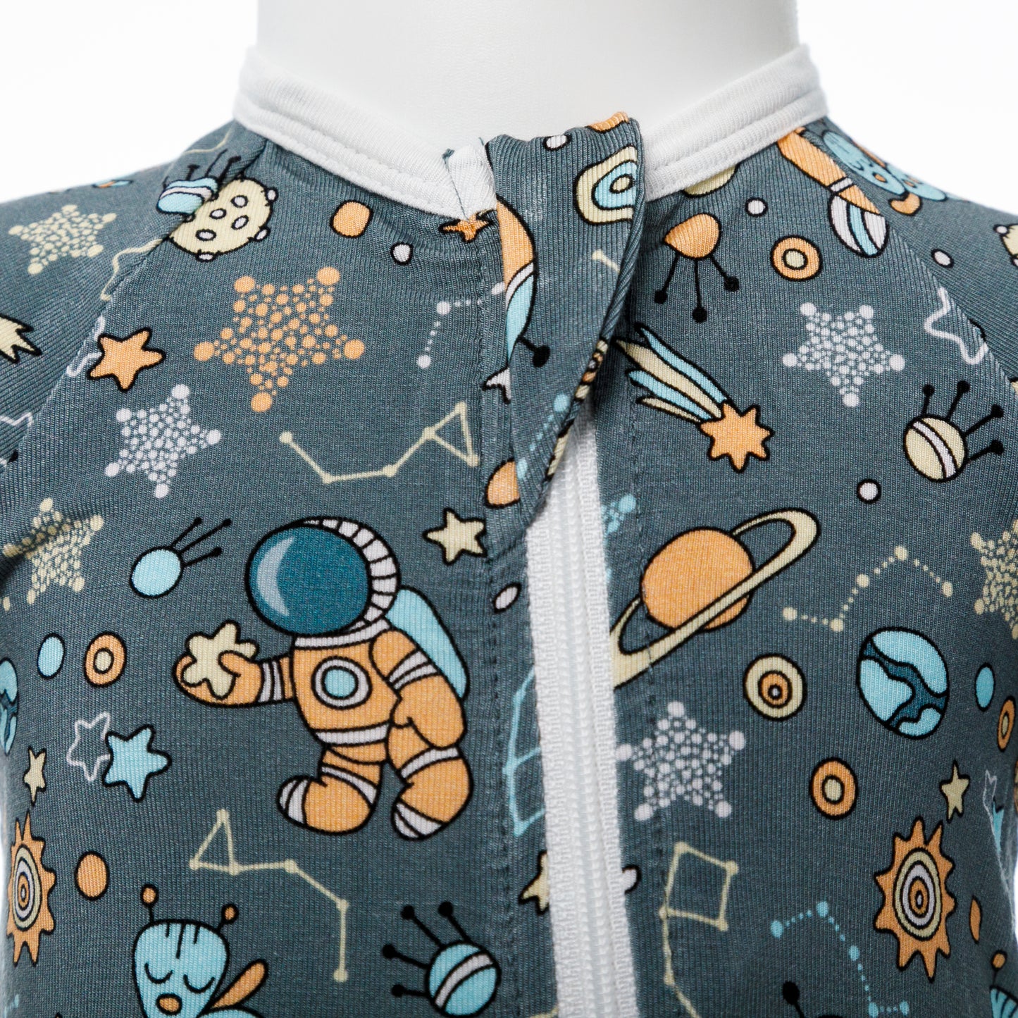 Vedere de aproape a fermoarului pe body-ul pentru bebeluși cu imprimeu cosmic.